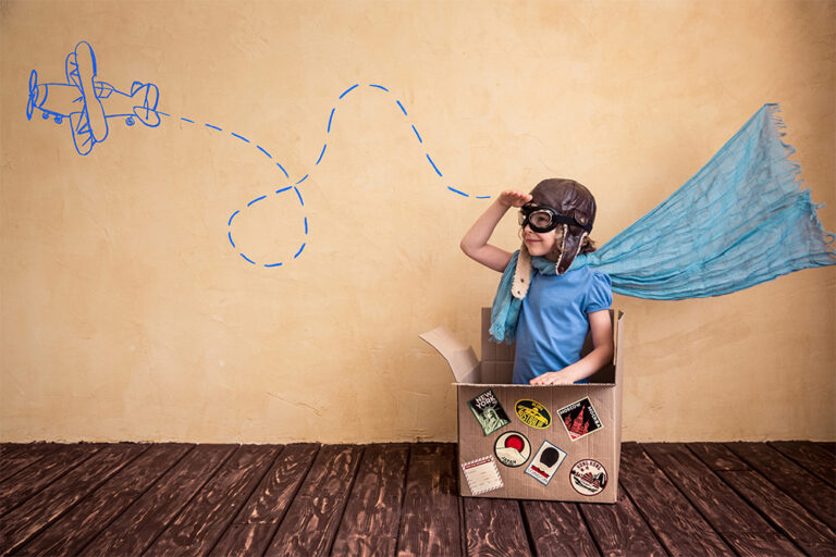 Photograph of a young child in a box pretending to be a pilot in a biplane.